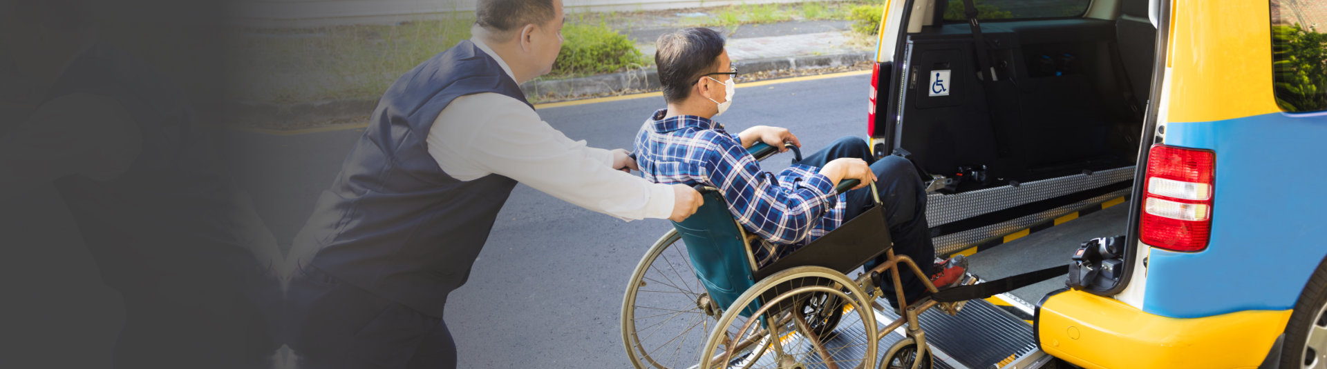 caregiver assiting man on wheelchair getting into vehicle